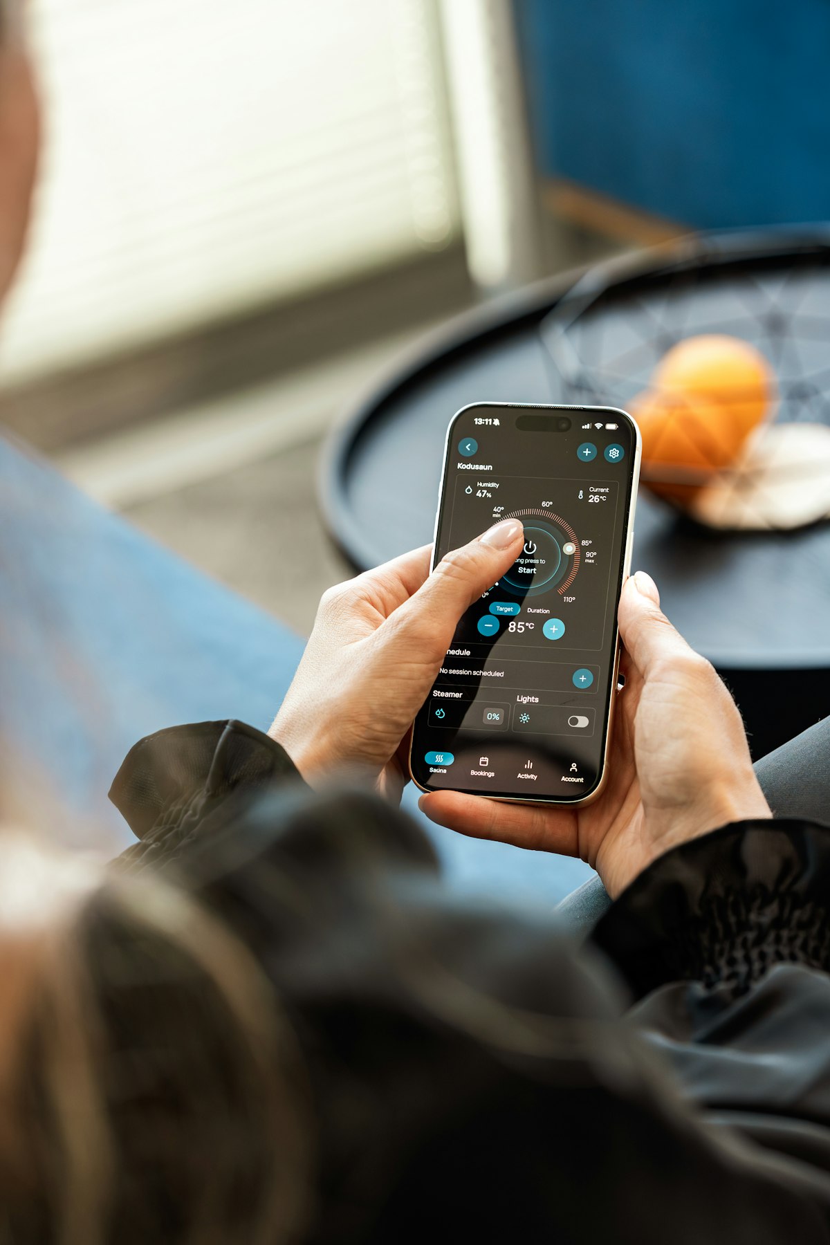 A hand holding a phone with a home control app open