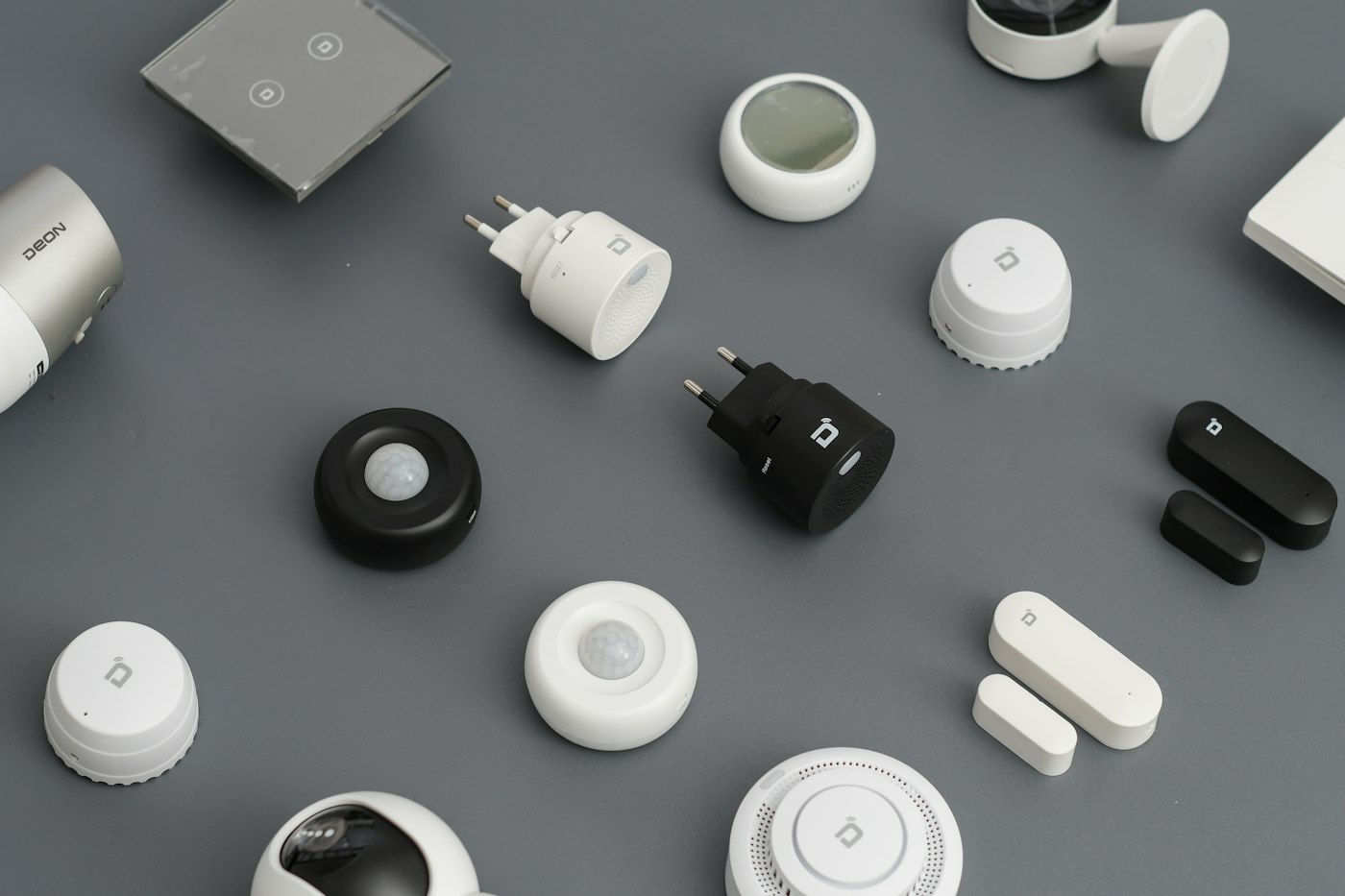 Small white smart home devices laid out on a grey surface