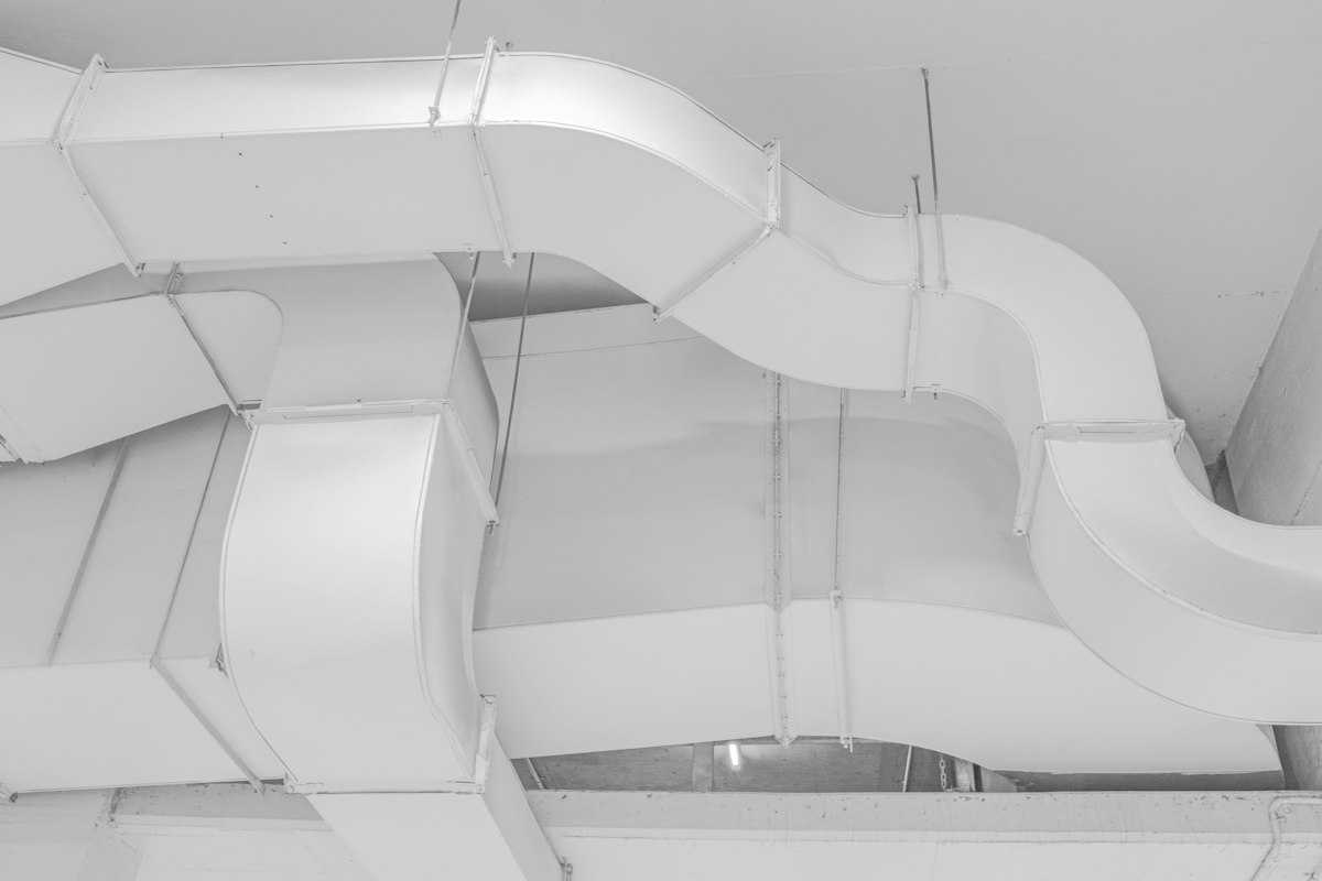 White ductwork bending across a ceiling, in black and white