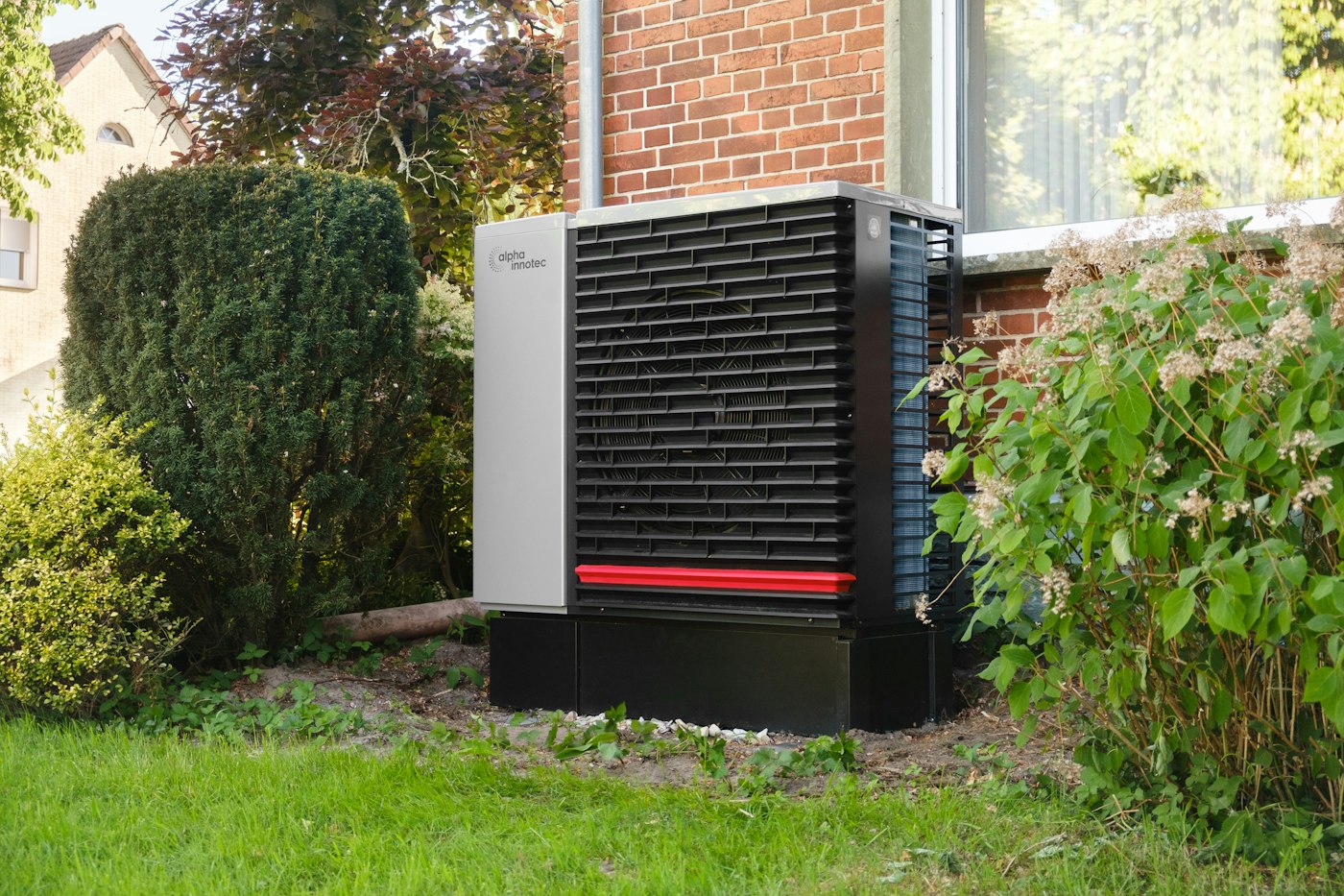 A heat pump outdoor unit standing next to a brick wall