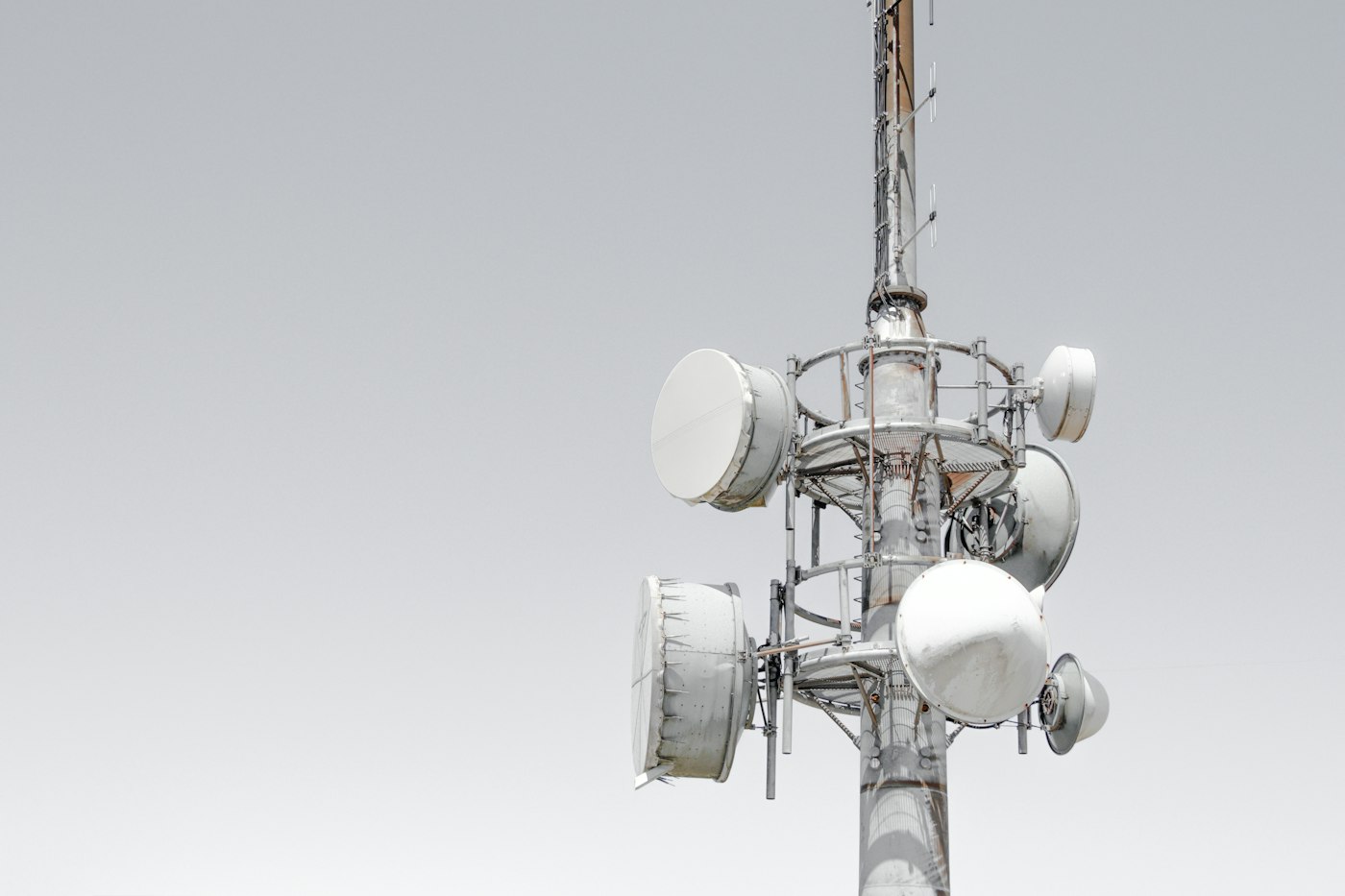 A white cellular antenna mast against a pale sky
