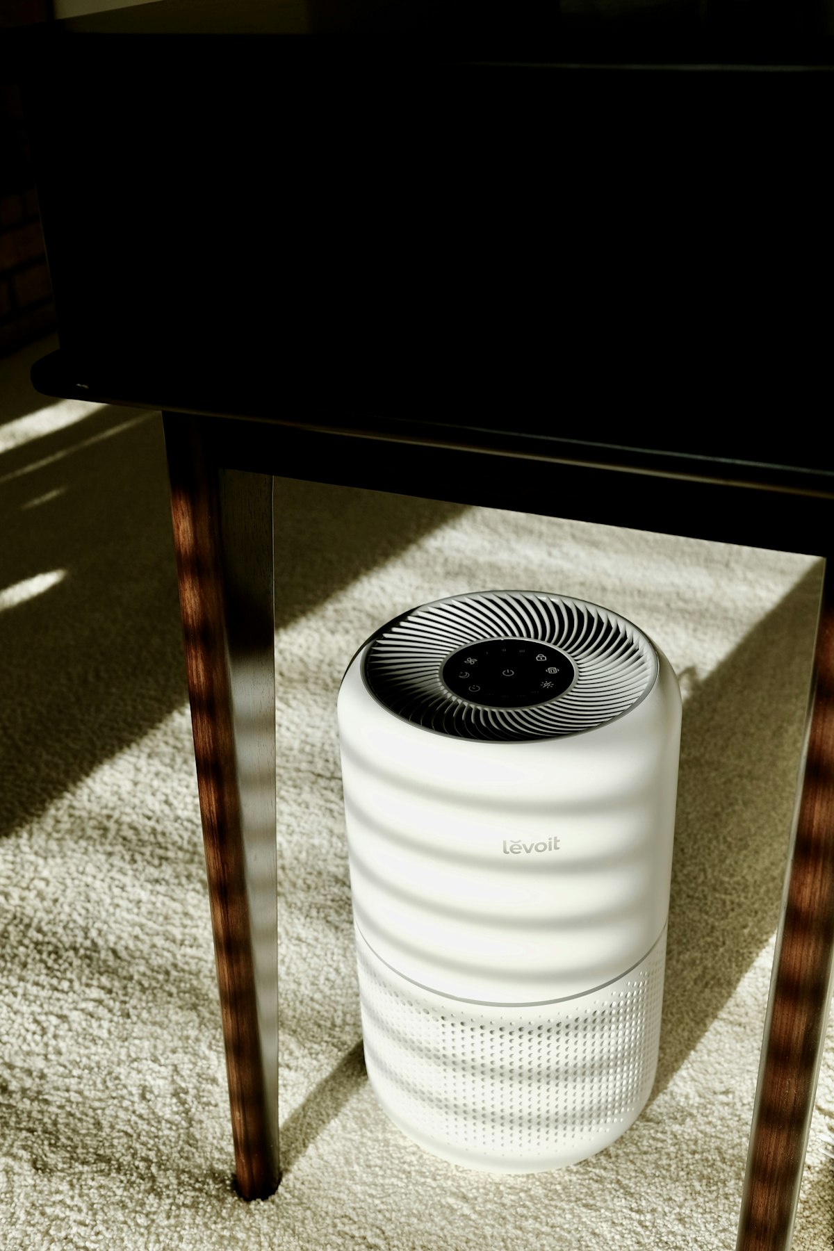 A white cylindrical air purifier on a wooden surface