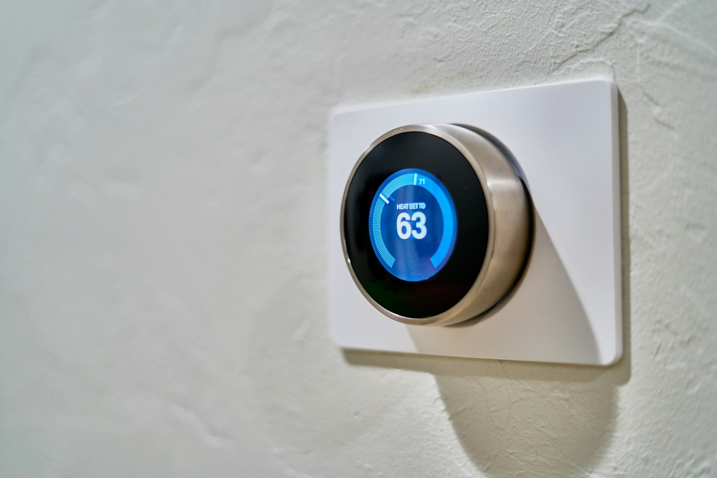 A round smart thermostat on a white wall